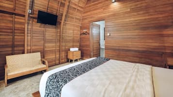 Un dormitorio con paredes de madera, una cama, un sofá, un televisor y una mesita.