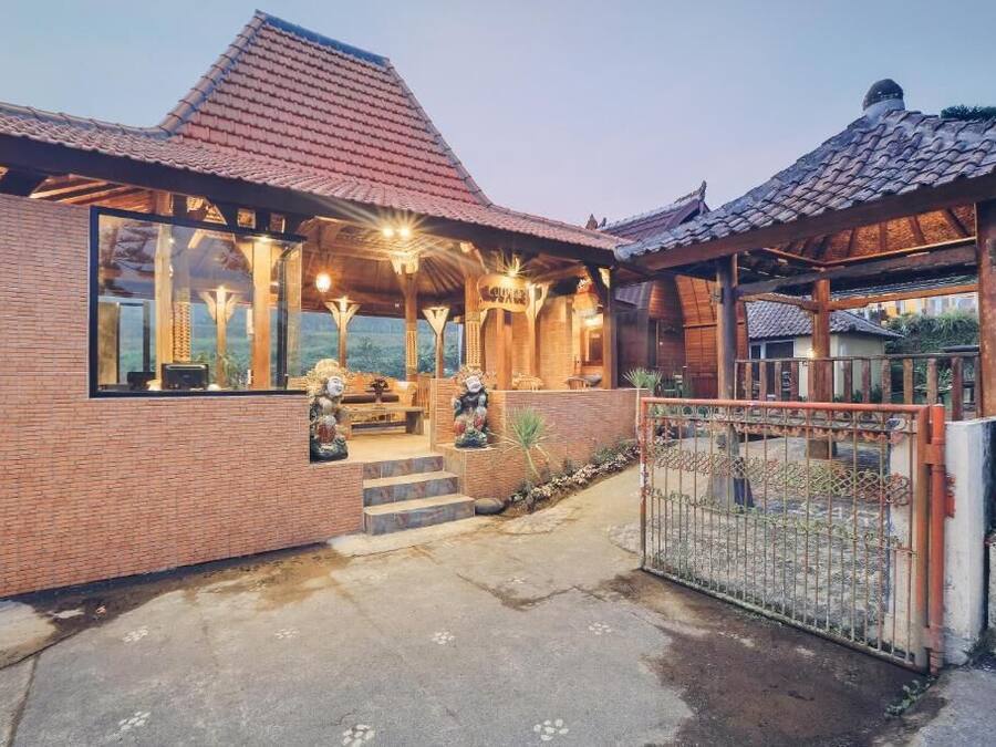 A traditional wooden house with a tiled roof, a brick exterior, and a gated entrance.