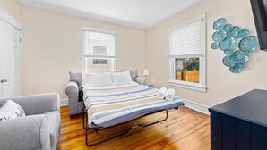 Une chambre à coucher avec un lit, une chaise, un bureau et une fenêtre avec des stores.