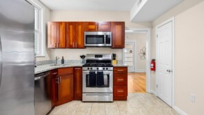 Une cuisine moderne avec des meubles en bois, des appareils électroménagers en acier inoxydable et un plan de travail en granit.