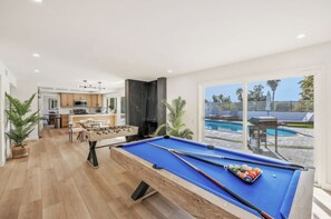 A pool table in a modern living room with a kitchen in the background and a pool outside. - Sin City Best Home By STRIP (Las Vegas)