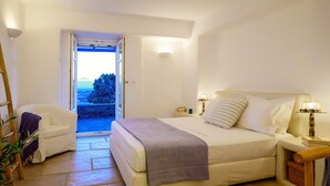 A bedroom with a bed, a chair, and a view of a pool. - Soho Villa in Paros (Tzanes)