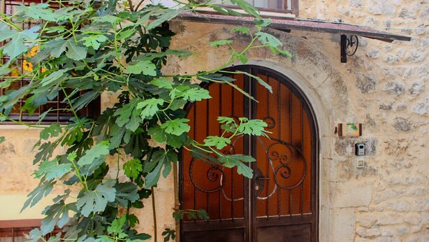 Ein Steinhaus mit schmiedeeisernem Tor, einem kleinen Balkon und einem Blumentopf.