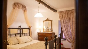 Ein Schlafzimmer mit Bett, Kommode, Spiegel und einem Fenster mit Vorhängen.