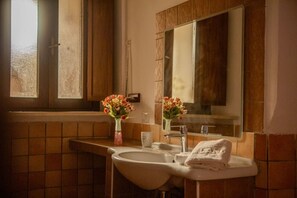 Une salle de bain avec un lavabo, un miroir et une fenêtre.