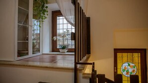 Eine Treppe mit hölzernem Geländer, ein Fenster mit Außenblick und eine Tür mit farbigem Glasdekor.