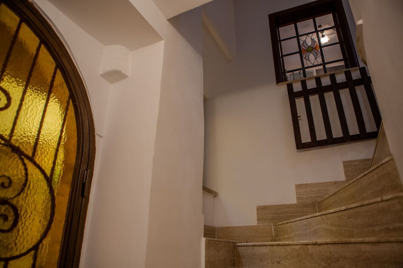 A staircase with a glass door and a window with a decorative grille.