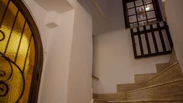 A staircase with a glass door and a window with a decorative grille.