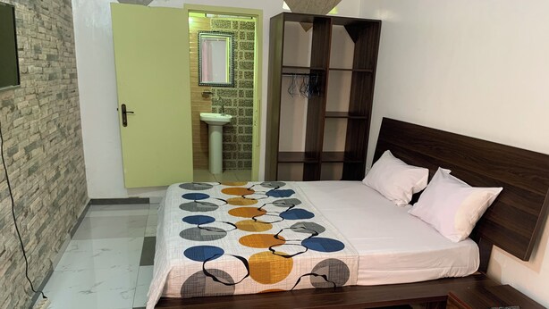 Ein Schlafzimmer mit Bett, Nachttischen, einem Kleiderschrank und einem durchgehenden Türrahmen sichtbaren Badezimmer.