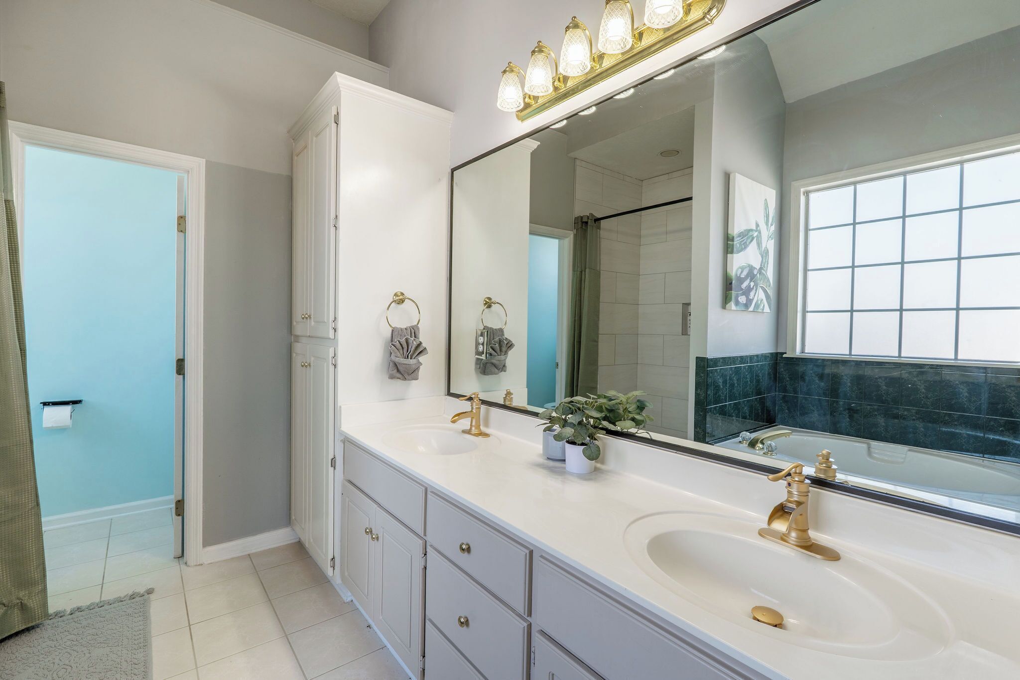 A bathroom with a large mirror, two sinks, and a bathtub.