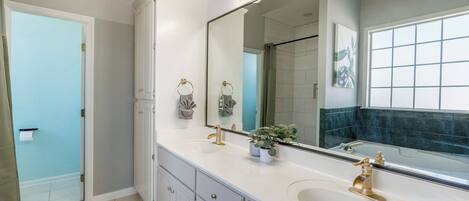 A bathroom with a large mirror, two sinks, and a bathtub.
