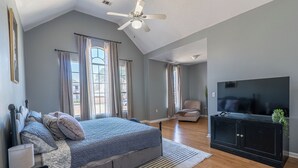 Quarto com uma cama grande, uma televisão e um ventilador de teto.