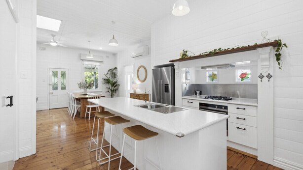 A modern kitchen with white cabinetry, a central island with bar stools, stainless steel appliances, and a view of the outdoors. - Ye Olde St Leonards Hotel Holiday Home, Pet Friendly, 300 metres to the Beach, Gas Log Fireplace (Saint Leonards)