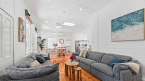 A spacious living room with a grey sofa, a round wooden coffee table, and a dining area with a white table and chairs. - Ye Olde St Leonards Hotel Holiday Home, Pet Friendly, 300 metres to the Beach, Gas Log Fireplace (Saint Leonards)