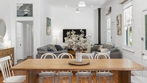 A dining area with a wooden table, white chairs, and a vase of flowers. - Ye Olde St Leonards Hotel Holiday Home, Pet Friendly, 300 metres to the Beach, Gas Log Fireplace (Saint Leonards)