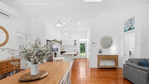 A spacious kitchen with wooden flooring, white cabinetry, and a dining area with a wooden table and chairs. - Ye Olde St Leonards Hotel Holiday Home, Pet Friendly, 300 metres to the Beach, Gas Log Fireplace (Saint Leonards)