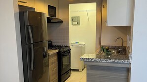 Une cuisine moderne équipée d’un réfrigérateur, d’une cuisinière, d’un four à micro-ondes et d’un petit îlot central avec un évier.