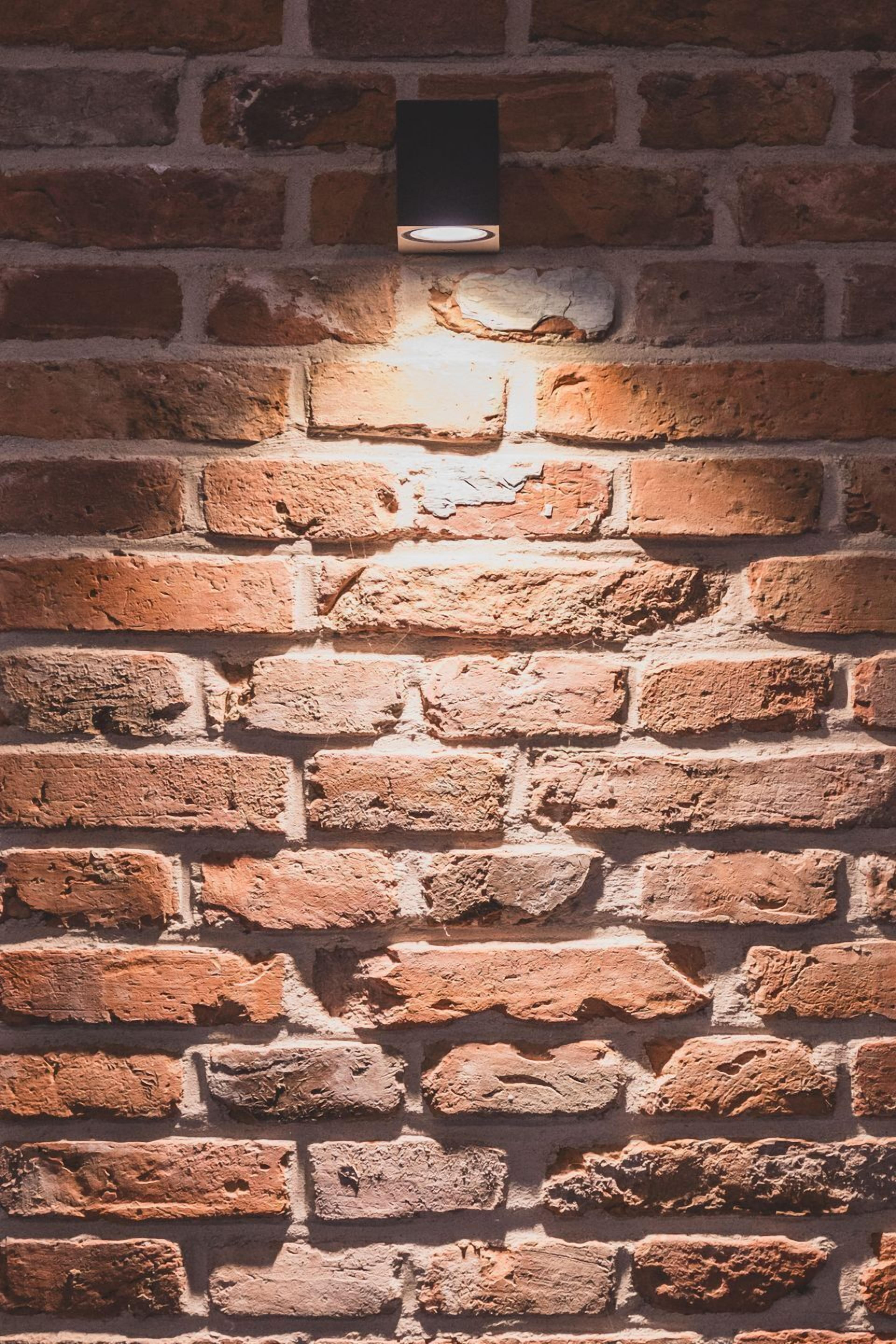A brick wall with a recessed light fixture.