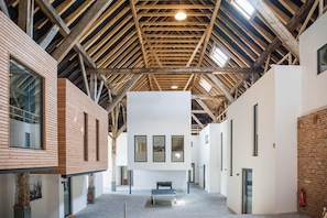 A spacious interior with high ceilings, exposed wooden beams, and a central seating area.
