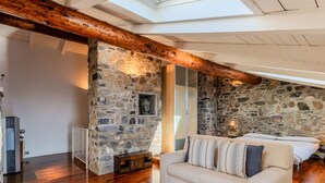 Una sala de estar acogedora con pared de piedra, vigas de madera, un sofá y una mesa de billar.