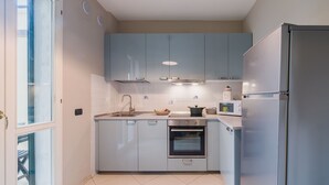 A modern kitchen with light blue cabinets, a stainless steel refrigerator, a built-in oven, and a microwave. - Casa Lido mare by Interhome (Lido di Camaiore)