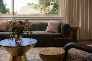 Ein Wohnzimmer mit einem dunklen Sofa, einem runden Couchtisch und einer Blumenvase.