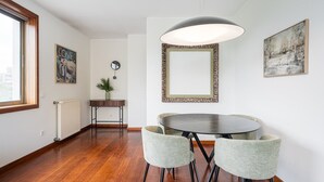 A dining area with a round table, two chairs, a pendant light, a mirror, and a plant. - GuestReady - Serene hideout in Leça da Palmeira (Porto)