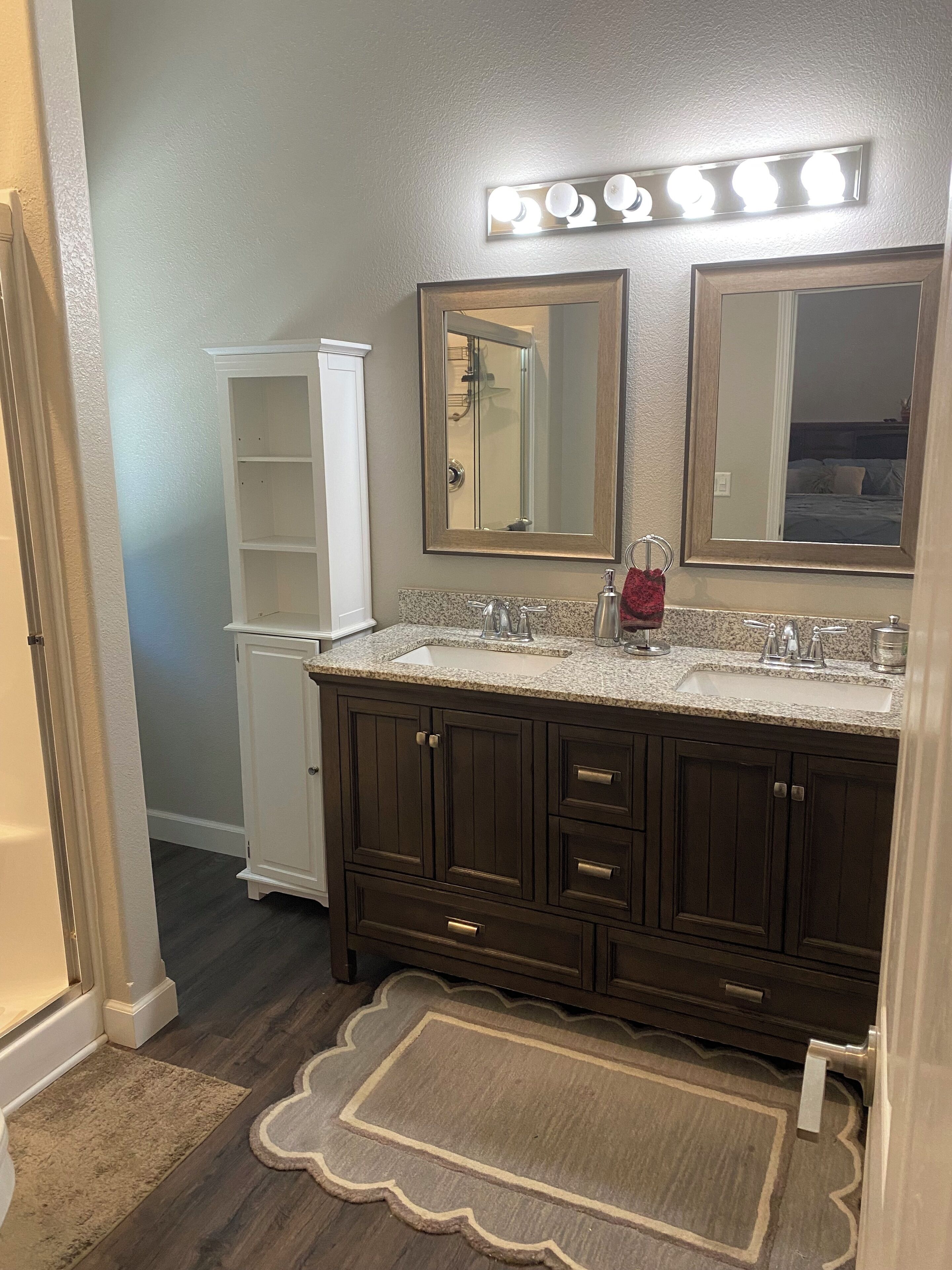 A bathroom with a double vanity, two sinks, a large mirror, and a vanity cabinet.
