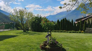 A well-maintained garden with a statue, a lawn, and a mountain backdrop. - Farm with small animals, beautiful and quiet location, with panoramic view (Latsch - Tarsch)