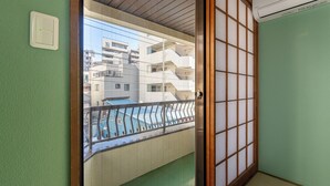 A traditional Japanese room with tatami flooring, a shoji screen door, and a view of a residential area with buildings and a swimming pool. - Asakusa Temple 4min Skytree 10min Japanese Cozy House  (Tokyo)