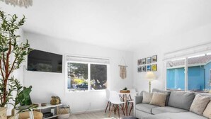 A living room with a sofa, a TV, a window, and a plant. - 1950's Surf Shack - 6 min walk to beach! (Santa Cruz)