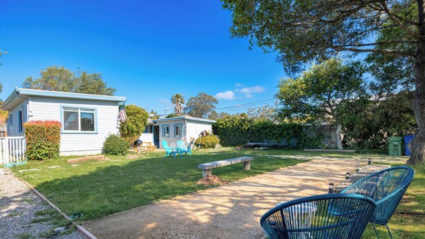 Una propiedad residencial con una casa pequeña, un patio empedrado y mobiliario de exterior.