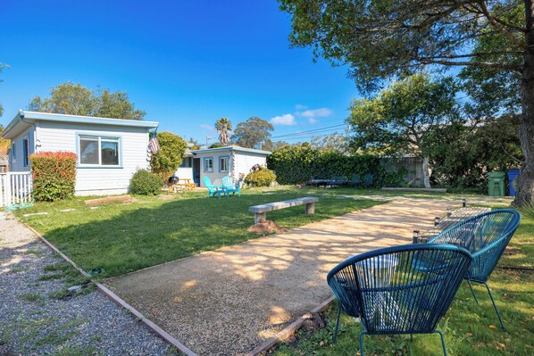 A residential property with a small house, a paved patio, and outdoor seating.
