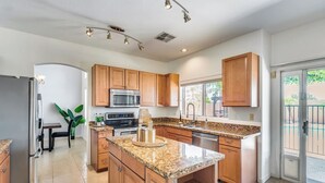 Una cocina moderna con encimeras de granito, armarios de madera y electrodomésticos de acero inoxidable, además de una isla grande.