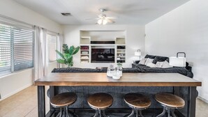 Una cocina moderna con una isla de madera y taburetes altos, televisión integrada y ventilador de techo.