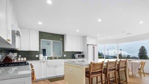 A modern kitchen with white cabinets, a central island, and a view of the outdoors. - 2 Bedroom Aptos Home With Ocean View! (Aptos)