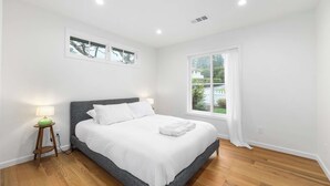 A bedroom with a bed, a nightstand, a window, and a wall-mounted picture. - 2 Bedroom Aptos Home With Ocean View! (Aptos)