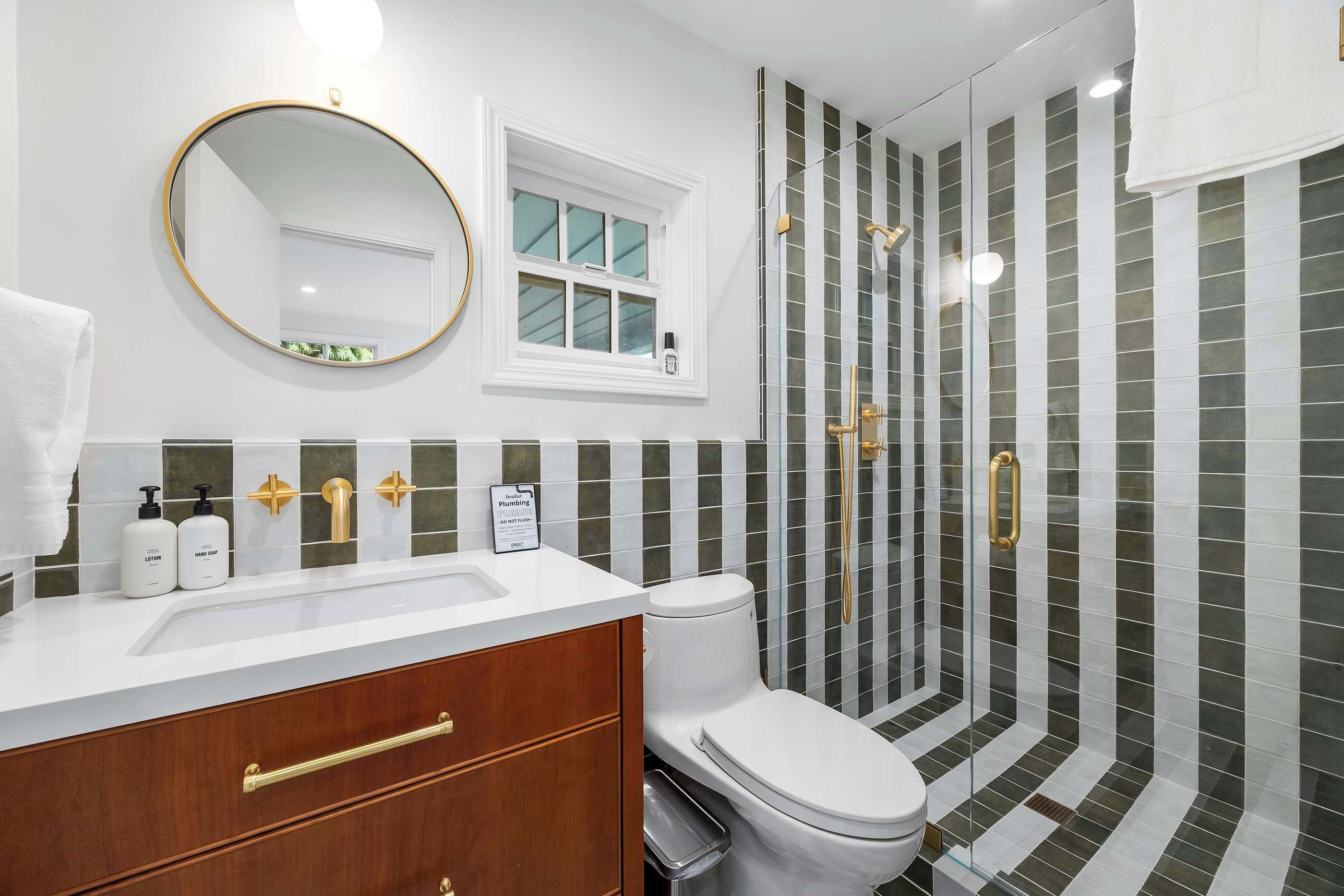 A bathroom with a white sink, a toilet, a mirror, and a shower with a glass door.
