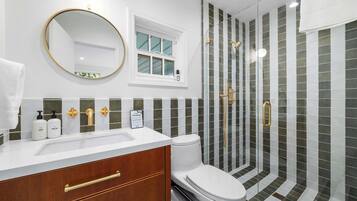 A bathroom with a white sink, a toilet, a mirror, and a shower with a glass door.