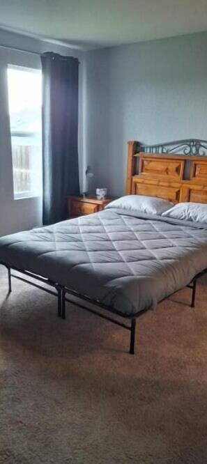 Cozy bedroom with a single bed, quilted mattress, and wooden headboard.