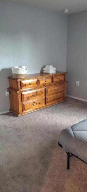 Comfortable room with a dresser, single bed, and light-colored carpet.
