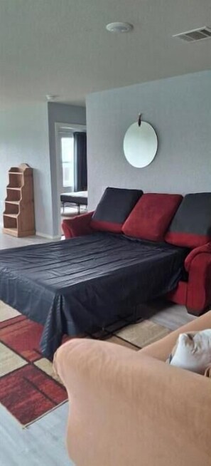 Relax in this serene bedroom with a large bed, round mirror, and comfortable sofa.