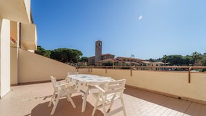 A terrace with a table and chairs, overlooking a town with a church tower and hotel buildings. - APPARTAMENTI GLI ORIZZONTI - ORIZZONTI N QUADRI 1 (Marina di Campo)