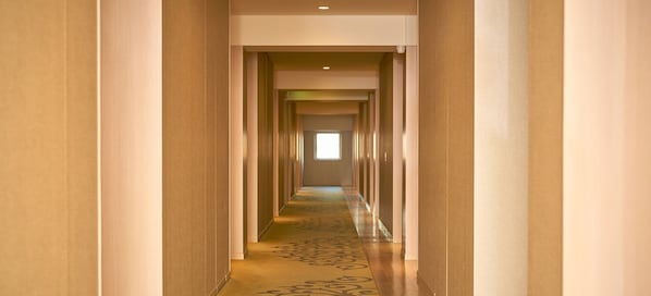 A long, narrow hallway with a patterned carpet and light-colored walls.