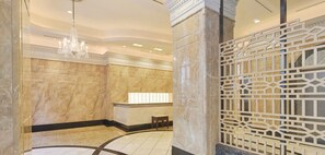 A lobby with marble walls, a chandelier, and a decorative partition.