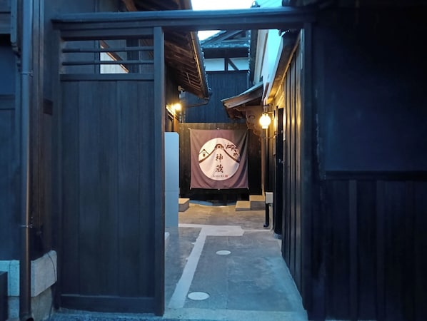 Edificio japonés tradicional con entrada de madera y un estandarte con caracteres japoneses.