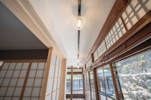 Una habitación japonesa tradicional con suelo de tatami, puertas correderas shoji y vistas a un jardín a través de amplias ventanas.