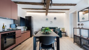 Eine moderne Küche mit Essbereich, Holzbalken an der Decke und Blick in das Wohnzimmer.