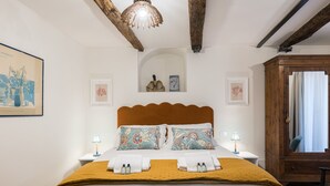Ein Hotelzimmer mit einem großen Bett, zwei Nachttischen, einem Holzschrank und einer Decke mit freiliegenden Balken.