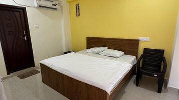 Une chambre avec un lit, un ventilateur de plafond, un appareil de climatisation et une chaise.